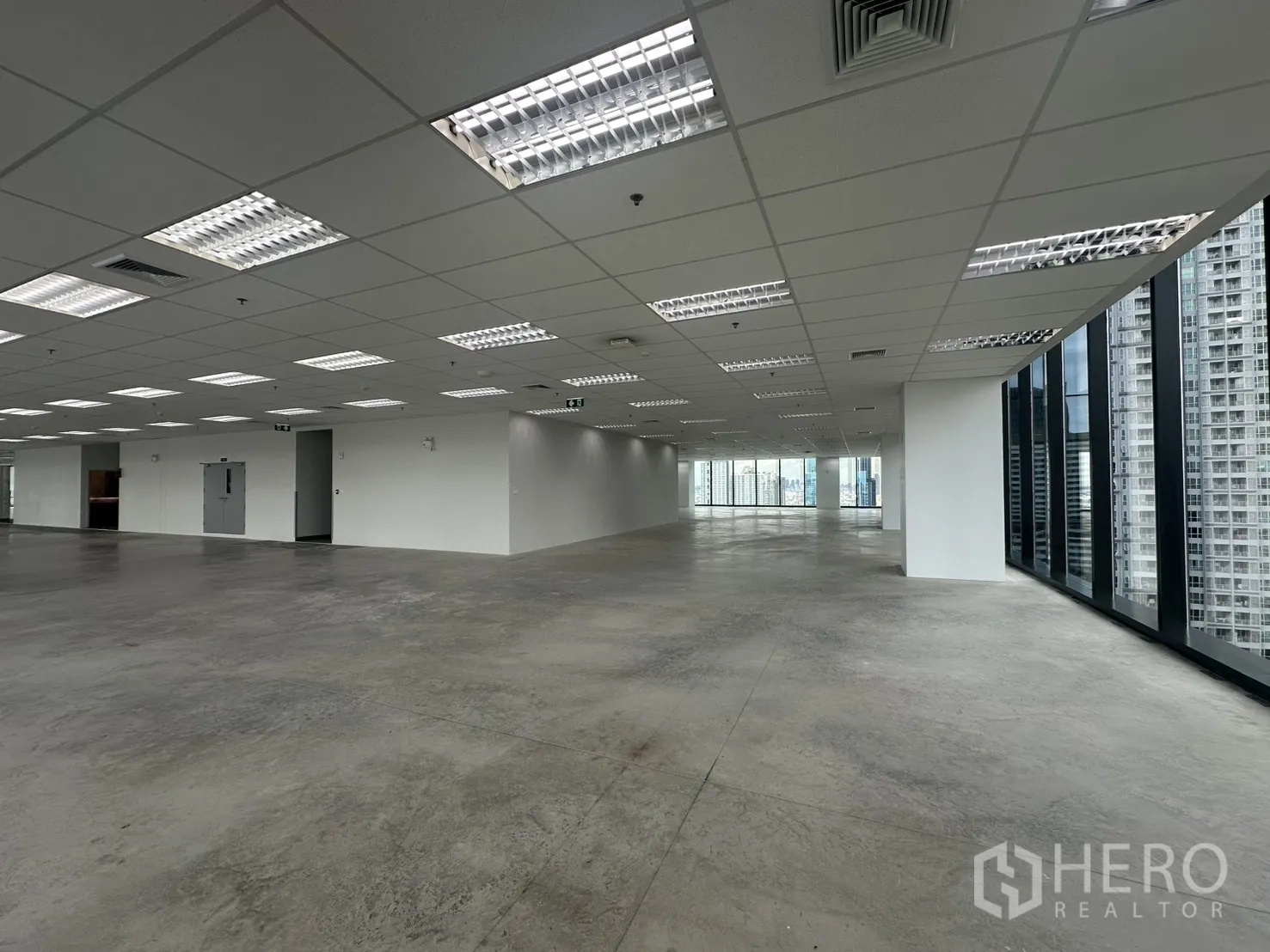 ออฟฟิศ for rent in Ratchathewi, Bangkok - พื้นออฟฟิศคอนกรีตเปลือย เพดานกริด และประตูหนีไฟบริเวณแกนกลาง