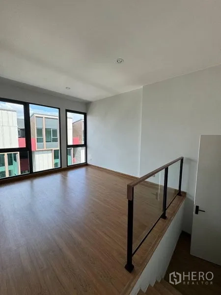 Townhouse for rent - Mezzanine-style bedroom with glass balustrade and expansive windows.