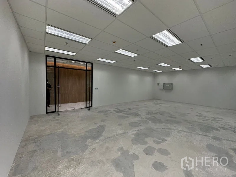 办公空间 出租 - 开放式办公区，玻璃入户门、荧光灯吊顶与水泥地面。