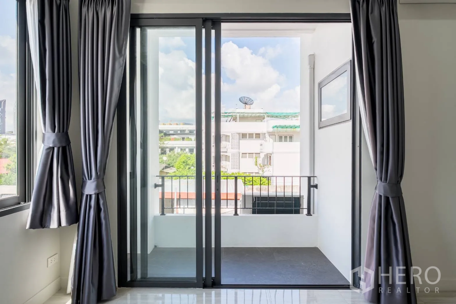 Home Office for rent in Khlong Toei, Bangkok - Small balcony through sliding glass doors with neighborhood and sky views.