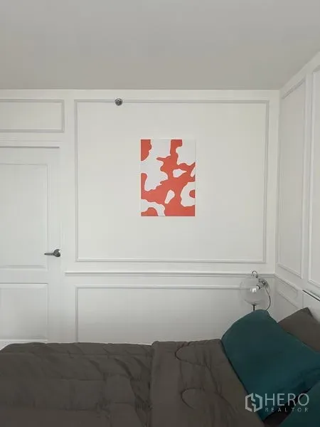 Condominium for rent or sale - Bedroom wall with bold red artwork, bedside lamp and paneled door detail.
