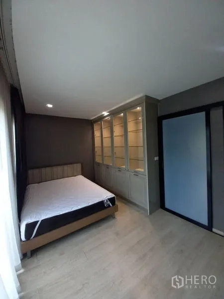 Townhouse for rent in Suan Luang, Bangkok - Guest bedroom with built-in glass-front cabinets and sliding door wardrobe.