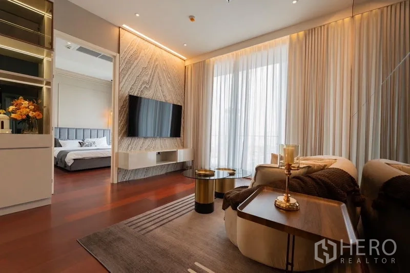 Condominium for rent in Watthana, Bangkok - Living room facing bedroom entrance with stone TV wall and soft ambient lighting.
