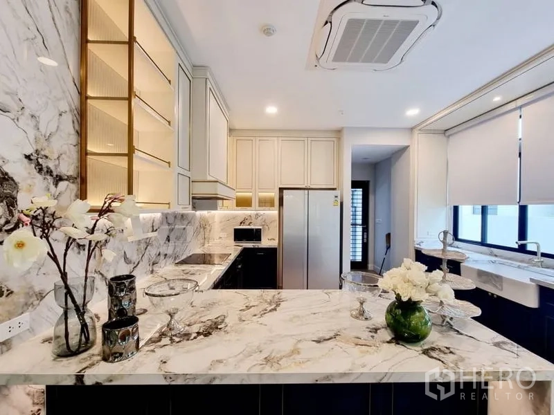 Detached House for rent in Saphan Sung, Bangkok - Modern marble kitchen with island counter, built-in cabinets, and stainless-steel refrigerator.