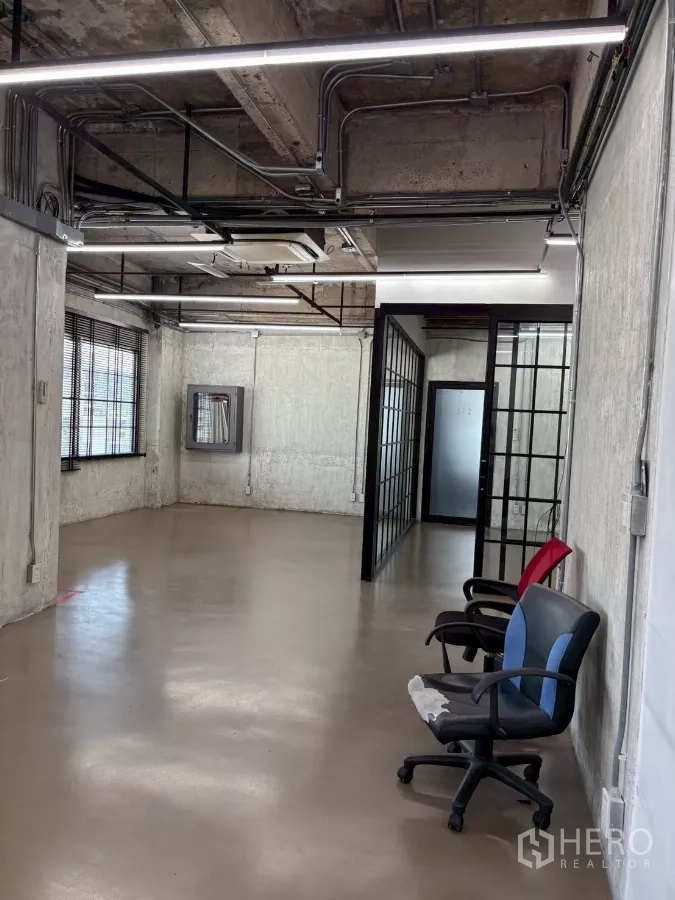 办公空间 出租在Watthana, Bangkok - 入口视角，磨砂玻璃门与网格玻璃墙，天花布满管线。