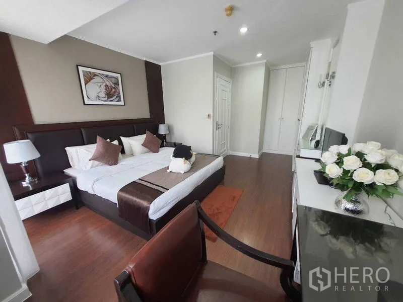 房间 出租在Watthana, Bangkok - 采光充足的卧室，特大床、床头柜与嵌入式衣柜，木地板。