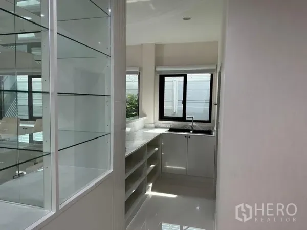 Detached House for sale in Saphan Sung, Bangkok - Bright pantry with marble counters, open shelving and a corner sink beside windows.