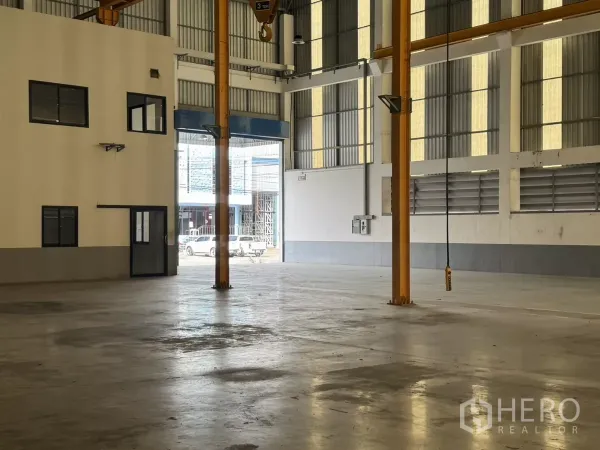 Factory for rent or sale in Bang Phli, Samut Prakan - Spacious warehouse interior facing roller shutter door with adjacent office.