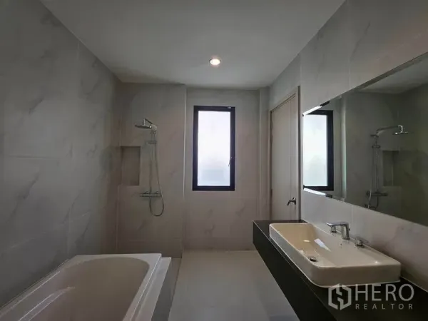 Detached House for rent in Saphan Sung, Bangkok - Spacious bathroom featuring a bathtub, separate shower, long vanity, and window for natural light.
