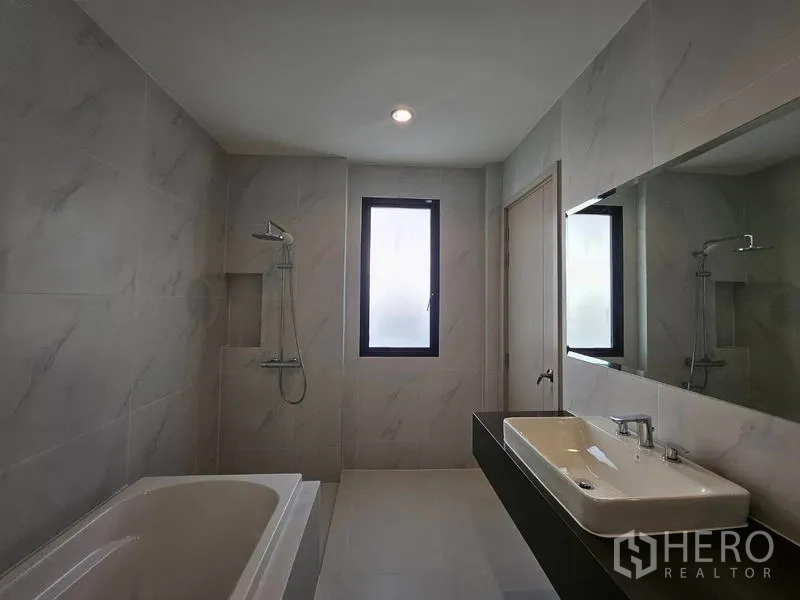 Detached House for rent in Saphan Sung, Bangkok - Spacious bathroom featuring a bathtub, separate shower, long vanity, and window for natural light.