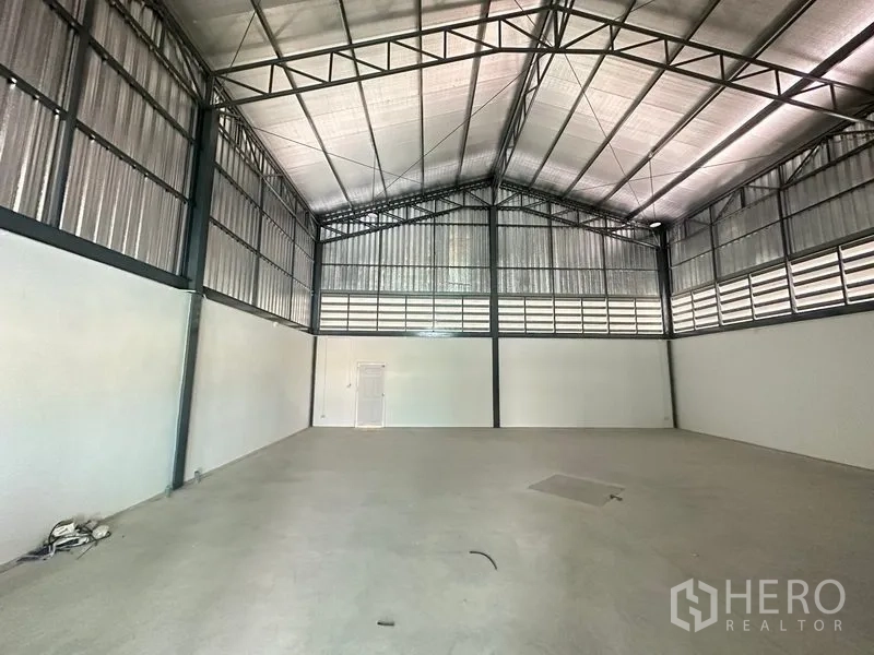 Factory for rent or sale in Bang Bua Thong, Nonthaburi - Spacious production area with natural side ventilation panels and a service door.
