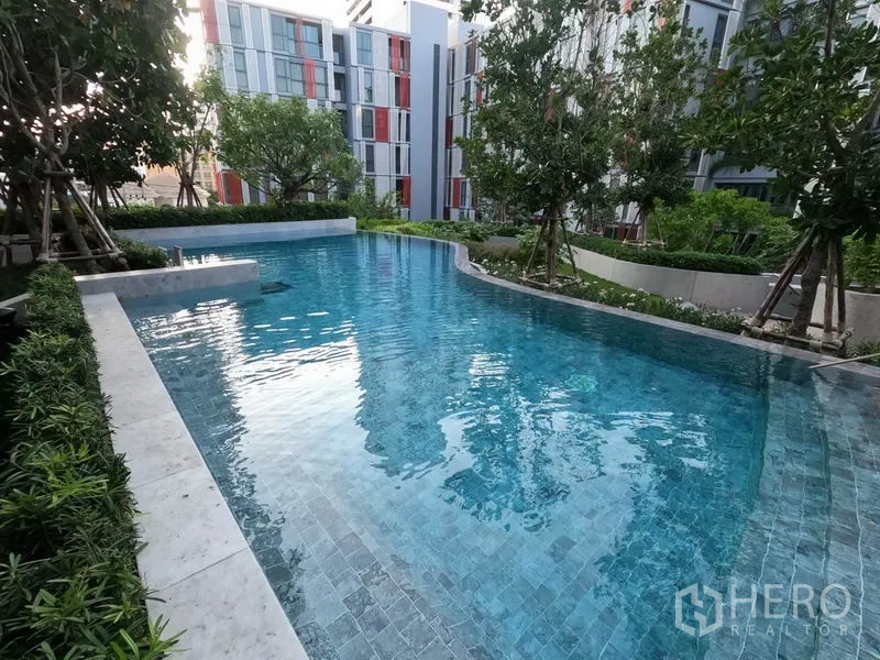 公寓 出租或出售在Watthana, Bangkok - 户外自由形泳池，被树木与现代低层建筑环绕。