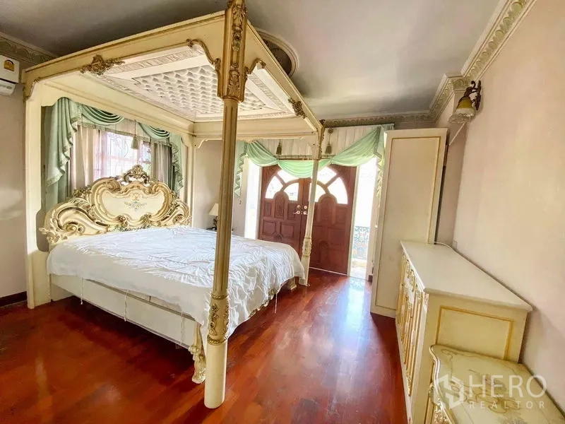 Detached House for rent or sale in Bang Khen, Bangkok - Guest bedroom with canopy bed, hardwood flooring, built‑in storage, and doors to a balcony.