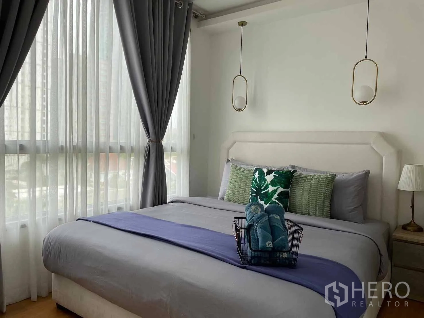 Condominium for rent in Watthana, Bangkok - Corner bedroom with large windows, pendant lights, and a king bed with a city outlook.