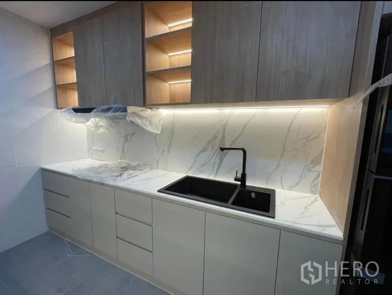 Condominium for rent - Close-up of kitchen counter with black sink and under-cabinet lighting.