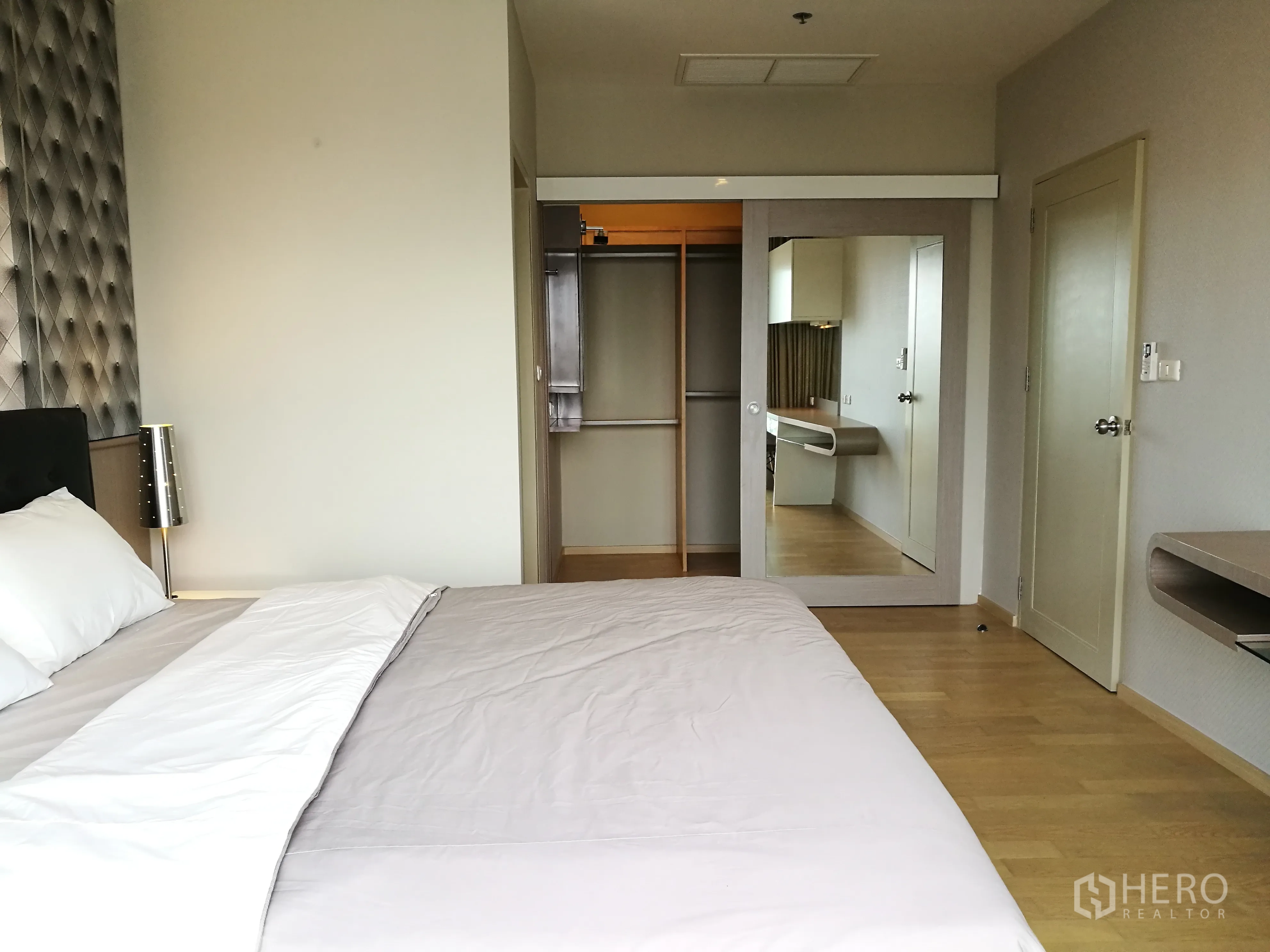 คอนโด for rent in Watthana, Bangkok - ห้องนอนสว่างพร้อมหัวเตียงบุผ้า โคมไฟข้างเตียง ตู้เสื้อผ้าบิ้วท์อินบานกระจก และพื้นไม้โทนอ่อน