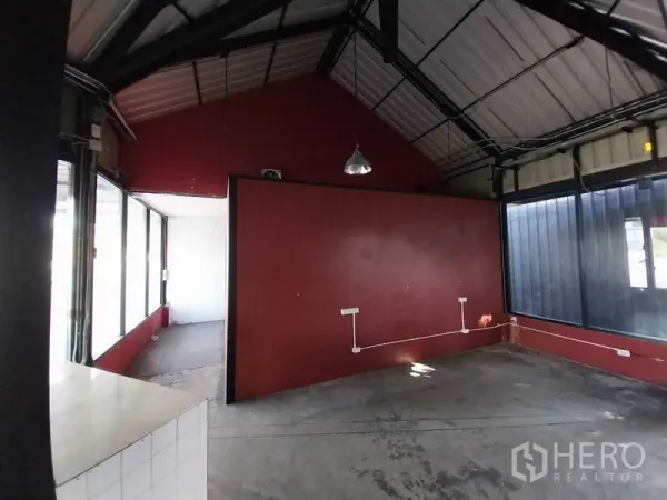Retail Space for rent in Khlong Toei, Bangkok - Industrial-style shop interior with a red partition wall, exposed beams, outlets, and abundant natural light.