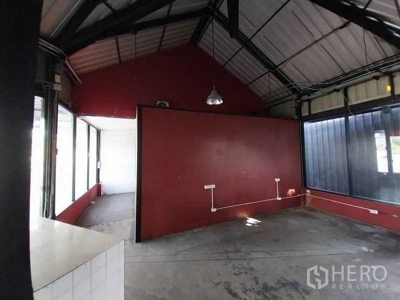 Retail Space for rent in Khlong Toei, Bangkok - Industrial-style shop interior with a red partition wall, exposed beams, outlets, and abundant natural light.