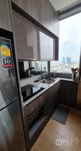 公寓 出租在Watthana, Bangkok - 紧凑厨房，内置家电、感应灶和景观窗。
