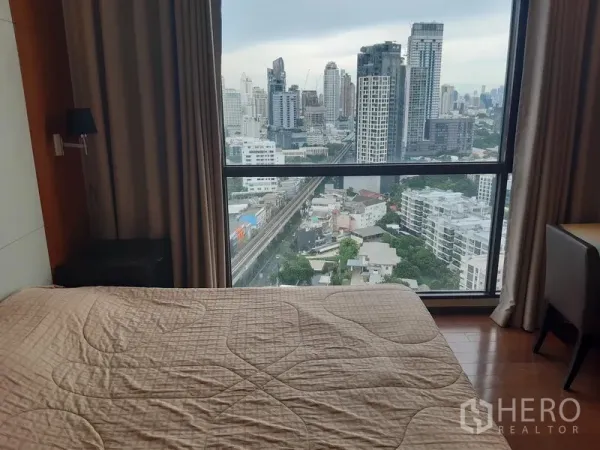 Condominium for rent or sale in Khlong Toei, Bangkok - Master bedroom featuring large window and panoramic city skyline outlook.