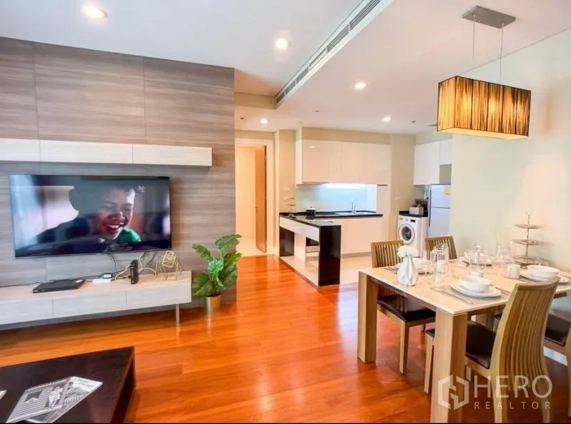 Condominium for rent in Khlong Toei, Bangkok - Open-plan lounge, dining and fitted kitchen with washing machine and wood flooring.