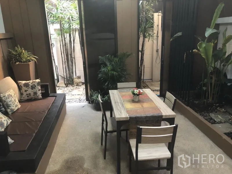 Townhouse for rent in Bang Kapi, Bangkok - Private courtyard with outdoor dining table, bench seating and tropical plants.