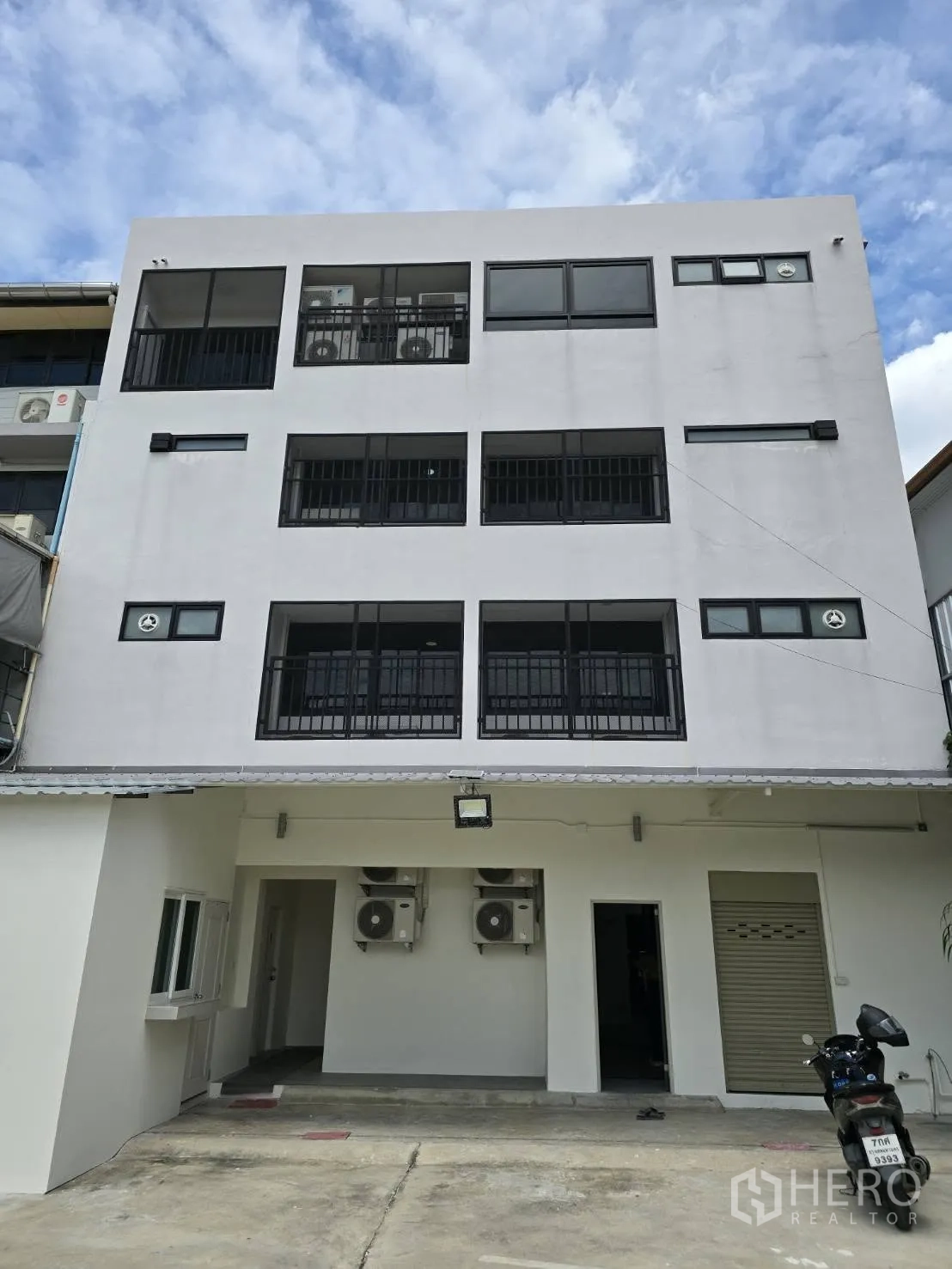 Home Office for rent in Chatuchak, Bangkok - Rear exterior of the building with balconies, air-conditioning units and covered parking area.