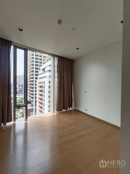 Condominium for rent or sale in Bang Rak, Bangkok - Bedroom with floor-to-ceiling corner windows, curtains and skyline view.