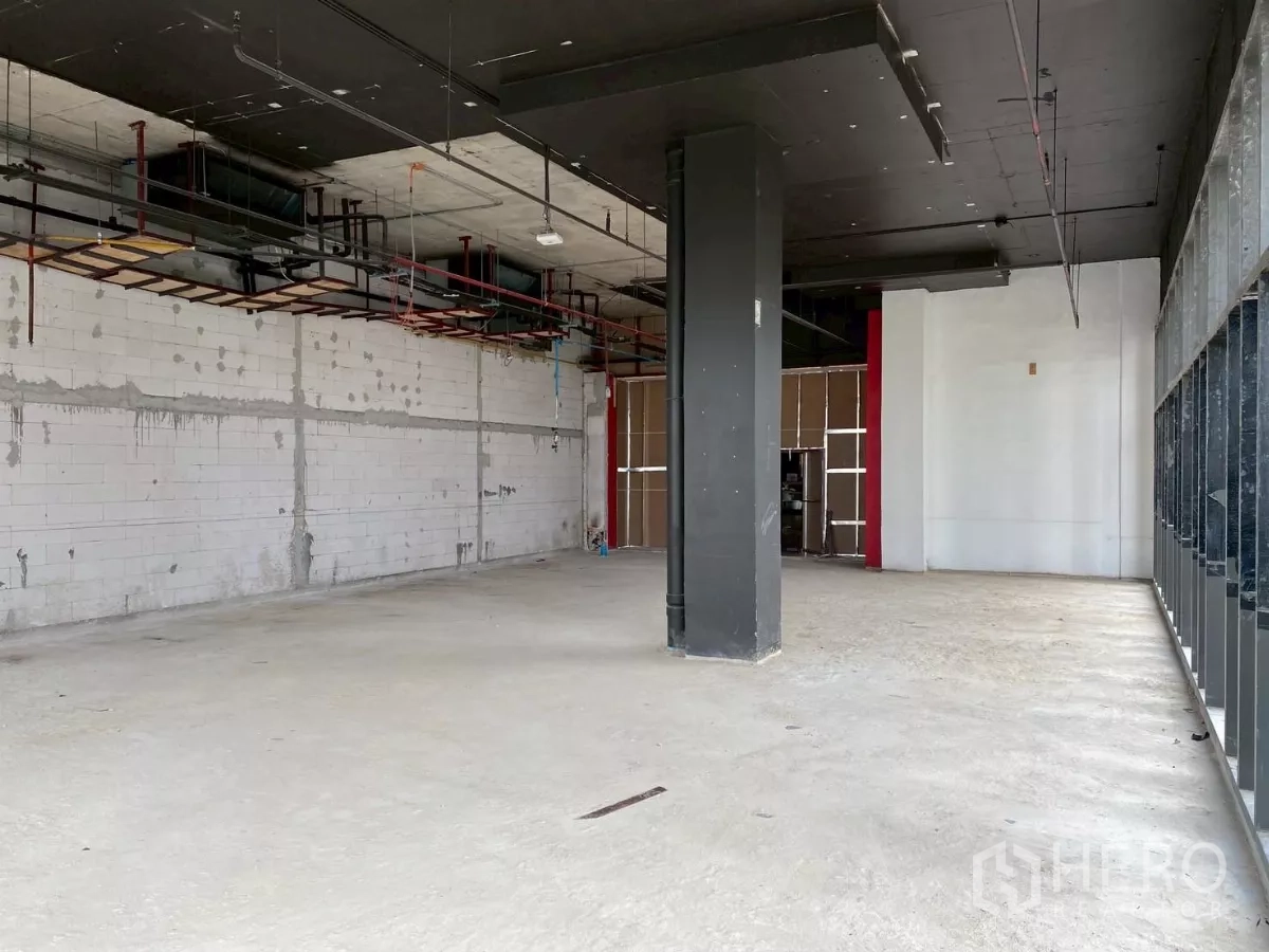 Retail Space for rent - Raw interior with black ceiling, structural column and extensive glazing.
