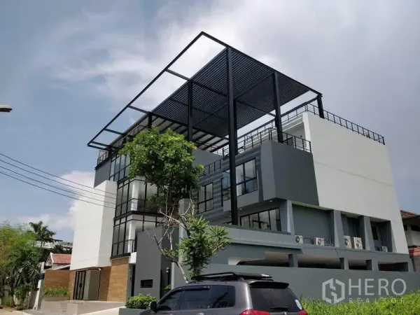 办公空间 出租在Prawet, Bangkok - 多层办公楼转角视角，屋顶钢结构与场内车位可见。