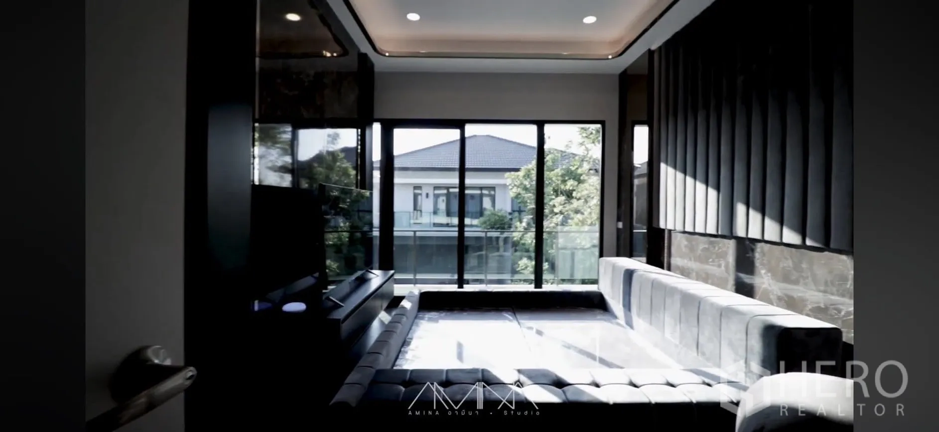 Detached House for rent in Saphan Sung, Bangkok - Living area with large sectional sofa opening to a balcony via floor-to-ceiling sliding doors.