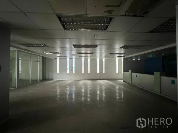 Shophouse for rent or sale in Khlong Toei, Bangkok - Spacious interior featuring a glass-partitioned meeting room and fluorescent ceiling lights.