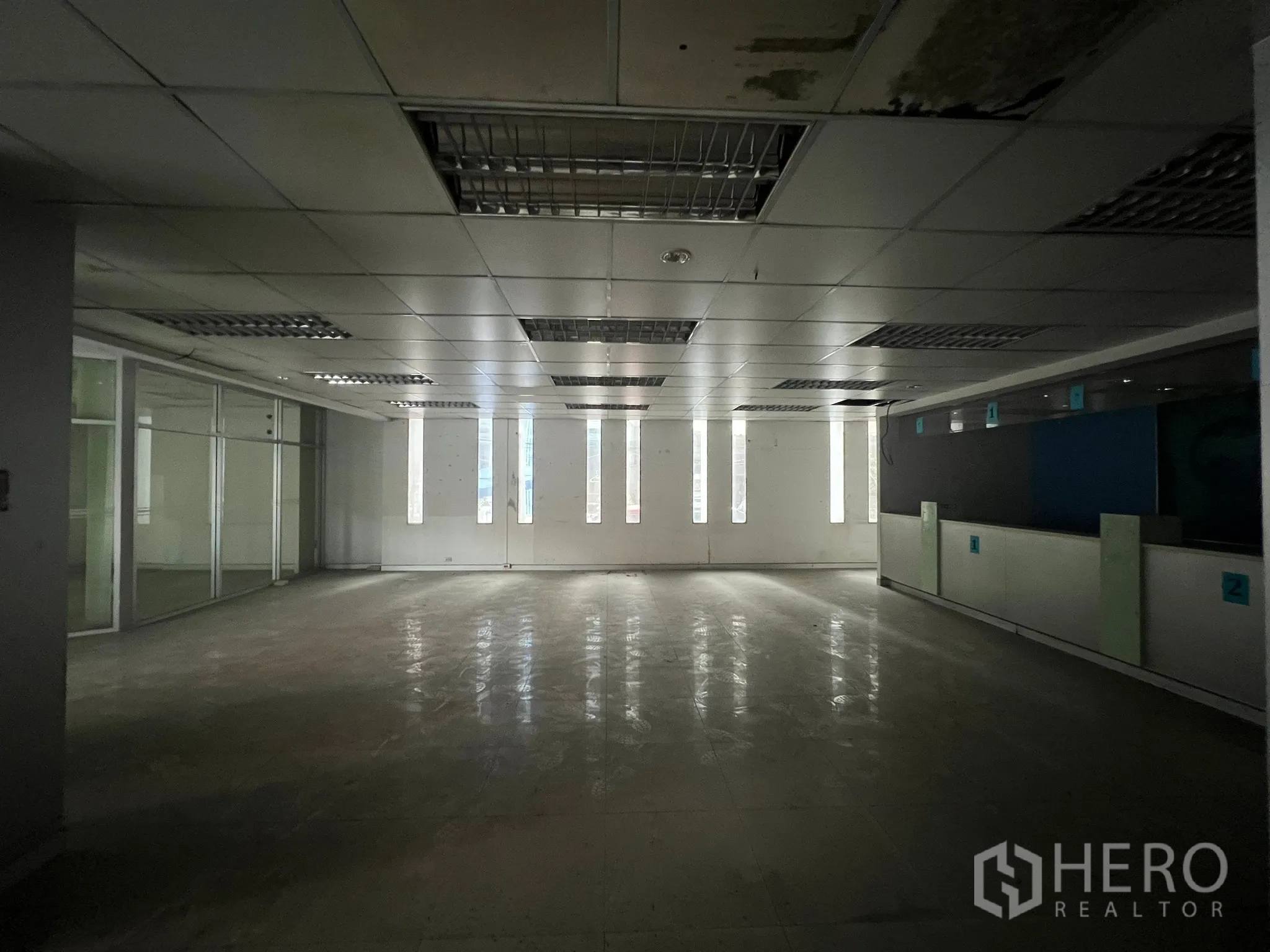 Shophouse for rent or sale in Khlong Toei, Bangkok - Spacious interior featuring a glass-partitioned meeting room and fluorescent ceiling lights.