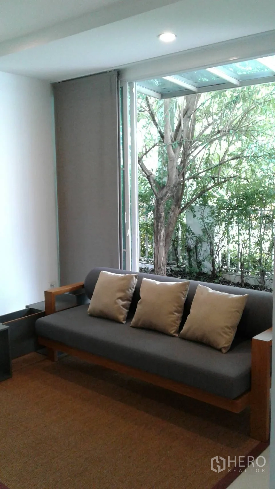 Townhouse for rent or sale in Suan Luang, Bangkok - Cozy lounge with gray sofa beside sliding glass doors to the garden.