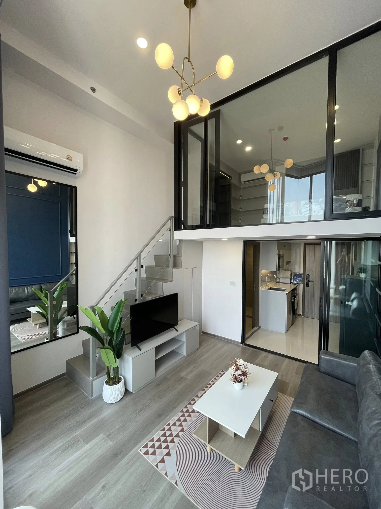 公寓 for rent in Khlong Toei, Bangkok - 复层起居区可见通往夹层的楼梯、电视柜、茶几、绿植与小厨房。