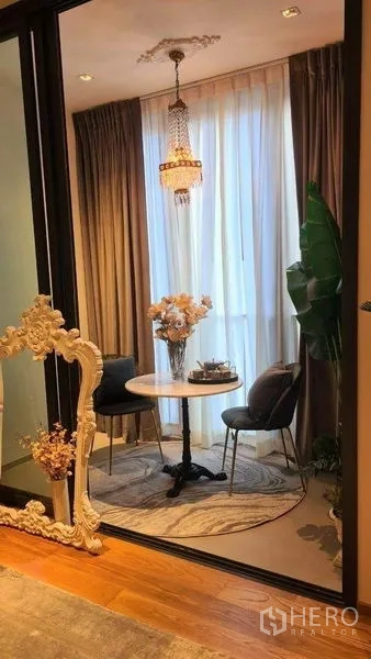 Condominium for rent in Khlong Toei, Bangkok - Cozy nook with round table, two chairs, tall curtains and chandelier.