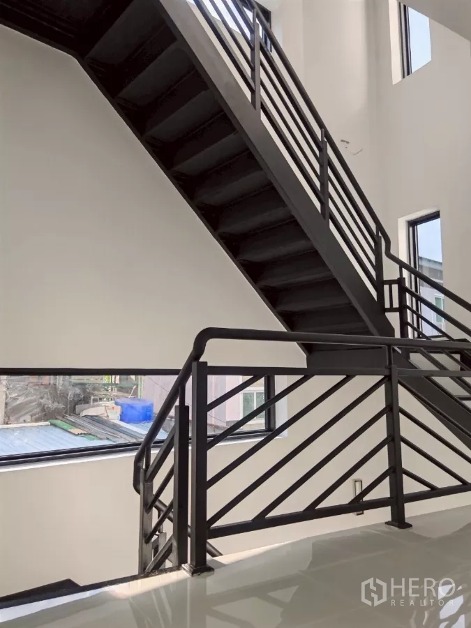 Detached House for rent in Wang Thonglang, Bangkok - Steel staircase with geometric railings beside large windows bringing light.