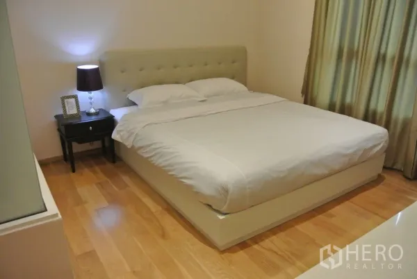 Condominium for rent in Watthana, Bangkok - Master bedroom with upholstered headboard, queen bed and large window dressed with blackout drapes.