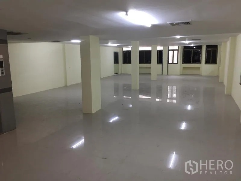 Home Office for rent in Watthana, Bangkok - Expansive empty office floor with support columns, windows on two sides and polished tiles.