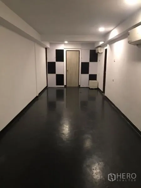 Home Office for rent or sale in Khlong Toei, Bangkok - Elongated office area with checkerboard accent panels and a door at the end.