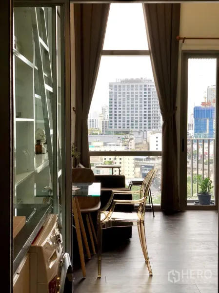 公寓 出租或出售在Khlong Toei, Bangkok - 客厅通向阳台的大窗，框出曼谷天际线景观。
