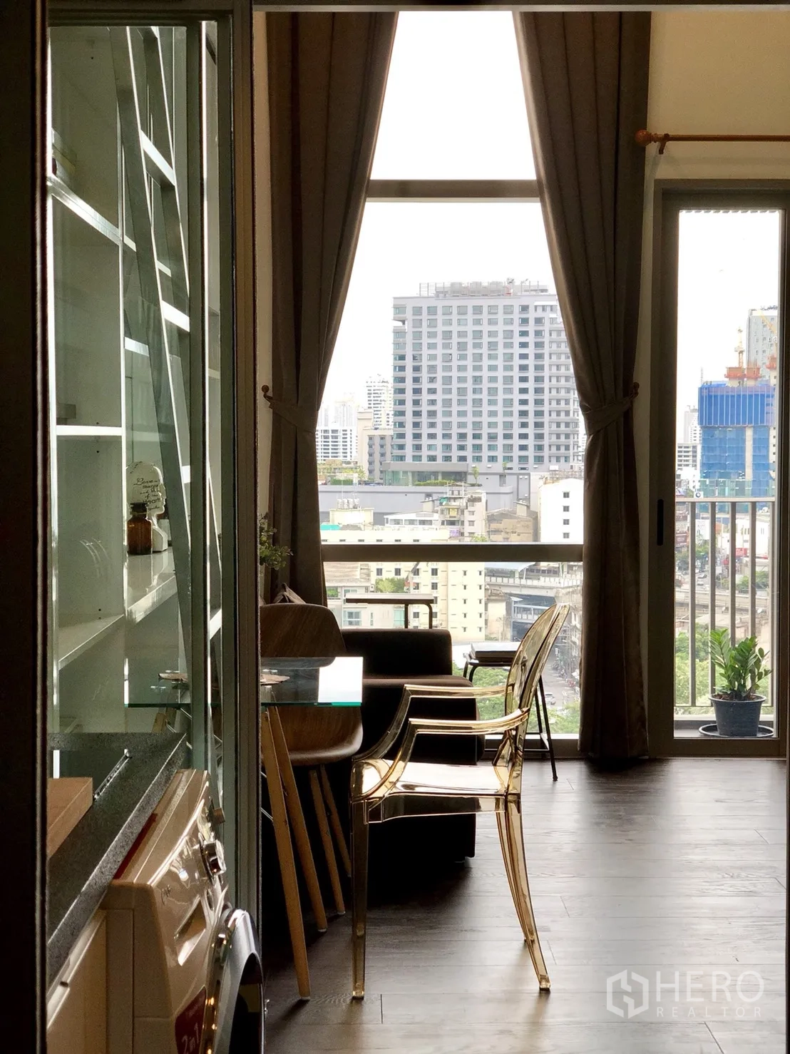 公寓 出租或出售在Khlong Toei, Bangkok - 客厅通向阳台的大窗，框出曼谷天际线景观。