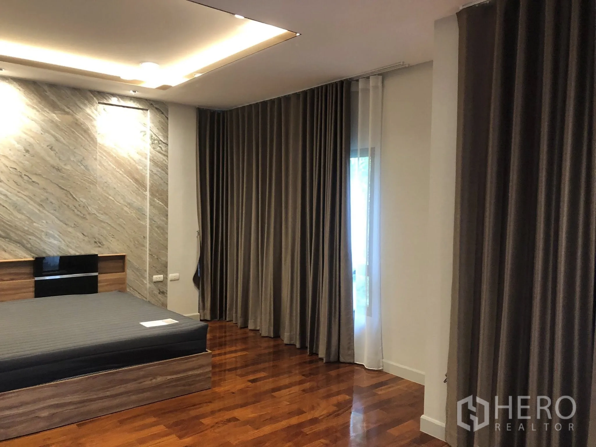 Detached House for rent in Bang Khae, Bangkok - Bedroom featuring a marble accent wall, recessed lighting and layered blackout curtains.