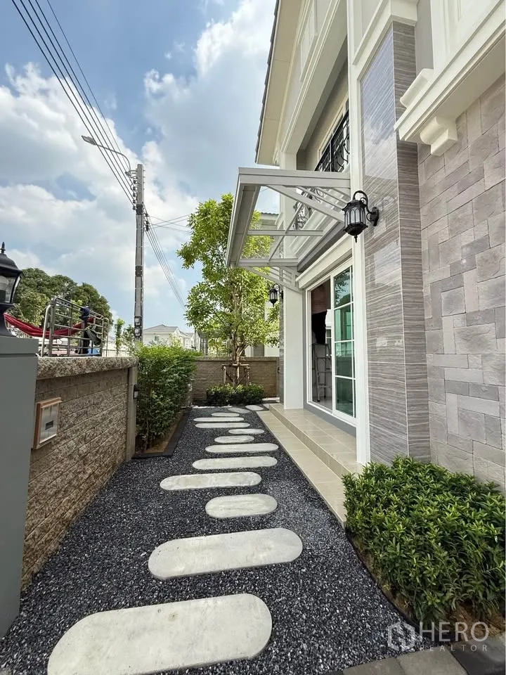 Semi-detached House for rent in Mueang Samut Prakan, Samut Prakan - Front garden with stepping-stone path, shrubs, and exterior lights by the entrance.
