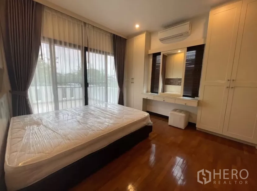 Detached House for rent in Chatuchak, Bangkok - Bedroom with balcony access, floor-to-ceiling windows and built-in wardrobe.