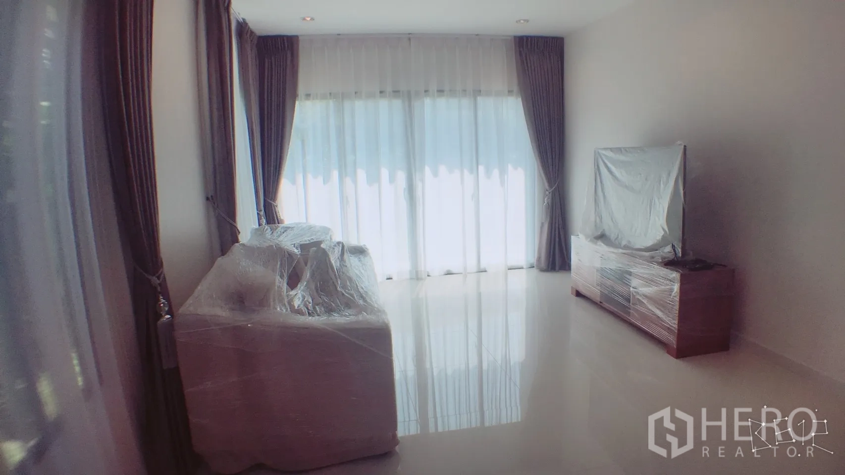 独立式住宅 出租在Suan Luang, Bangkok - 宽敞客厅，推拉落地门，包裹保护的沙发与电视柜，采光良好。