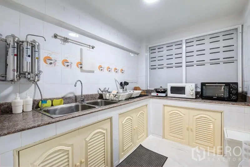 联排别墅 出租在Bang Rak, Bangkok - 白色瓷砖厨房，双水槽、石材台面和小家电。