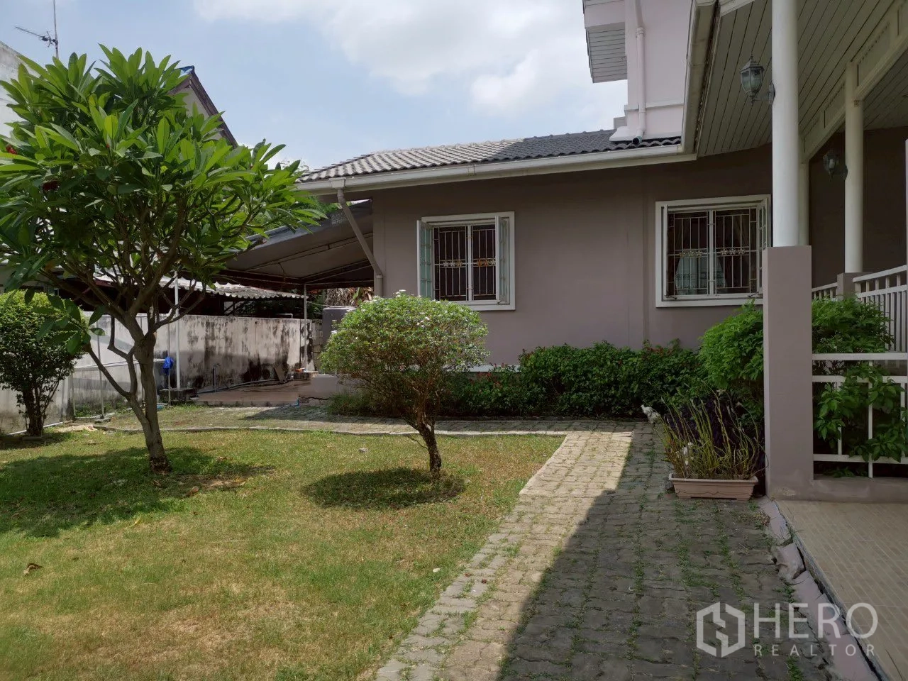 独立式住宅 出售在Phra Khanong, Bangkok - 沿屋花园步道，灌木、窗户与檐口。