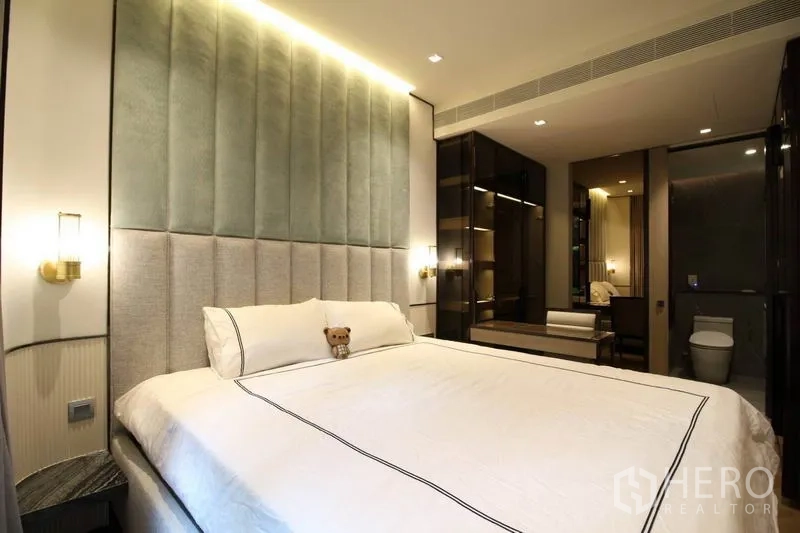公寓 出租在Watthana, Bangkok - 主卧配软包床头与床头壁灯，可见套内卫浴入口。