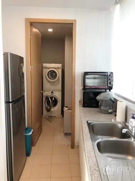 Condominium for rent in Khlong Toei, Bangkok - Utility area off the kitchen with double sink, countertop appliances and stacked washer and dryer.